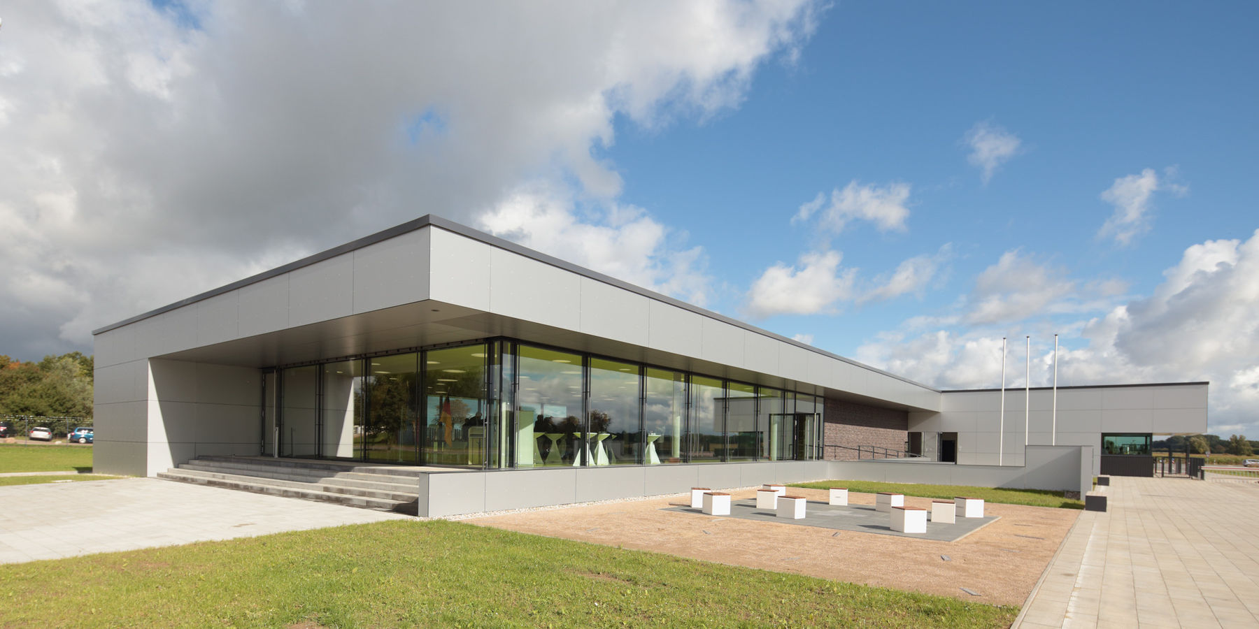 Sonnige Aussichten: Offene und freundliche Architektur für das Versorgungsgebäude. Im Vordergrund befindet sich der Aufenthaltsbereich mit der Kunst am Bau - zum Sitzen im Freien bestens geeignet. © 2015 Betrieb für Bau und Liegenschaften Mecklenburg-Vorpommern