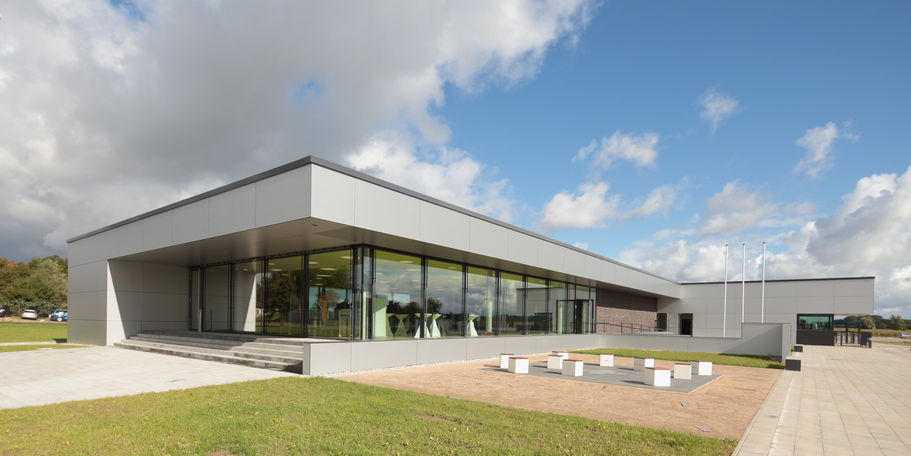 Sonnige Aussichten: Offene und freundliche Architektur für das Versorgungsgebäude. Im Vordergrund befindet sich der Aufenthaltsbereich mit der Kunst am Bau - zum Sitzen im Freien bestens geeignet. © 2015 Betrieb für Bau und Liegenschaften Mecklenburg-Vorpommern