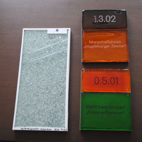 Modelle des Künstlers Olaf Thaler, links: mit Glasbruch gefüllte Verbundscheibe für den Wegweiser, rechts Modell der Türbeschriftung: Die Raumnummern und Bezeichnungen im Gebäudeinnern bestehen aus dicken farbigen gegossenen Glasplatten, die auf eine poli © 2016 Betrieb für Bau und Liegenschaften Mecklenburg-Vorpommern