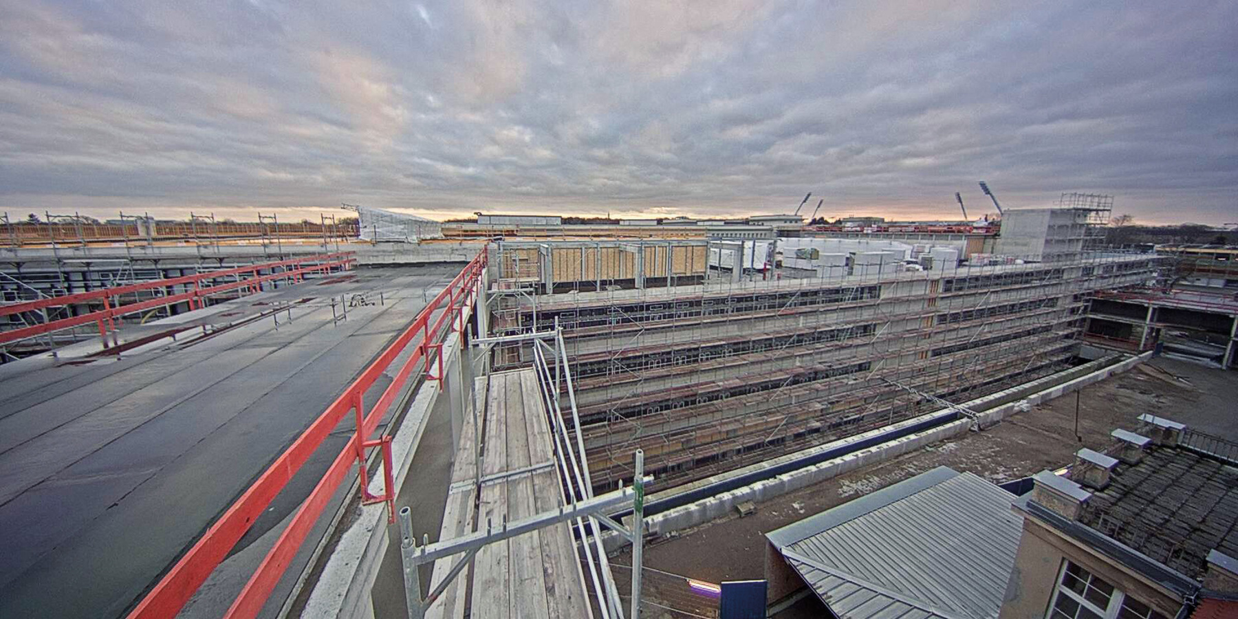 Blick auf den Neubau der Zentralen Medizinischen Funktionen am Abend des 6. März 2018. Im Hintergrund sind die Flutlichtmasten des Ostseestadions zu sehen - davor oben auf dem Rohbau der Hubschrauberlandeplatz. © 2018 Betrieb für Bau und Liegenschaften Mecklenburg-Vorpommern