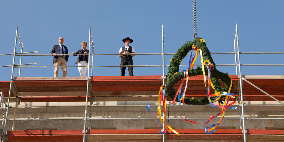 v. l.: Robert Klaus und Cornelia Gauß vom BBL M-V, Zimmermann Pruhs von der Firma Köthenbürger und der Richtkranz. © 2018 Betrieb für Bau und Liegenschaften Mecklenburg-Vorpommern
