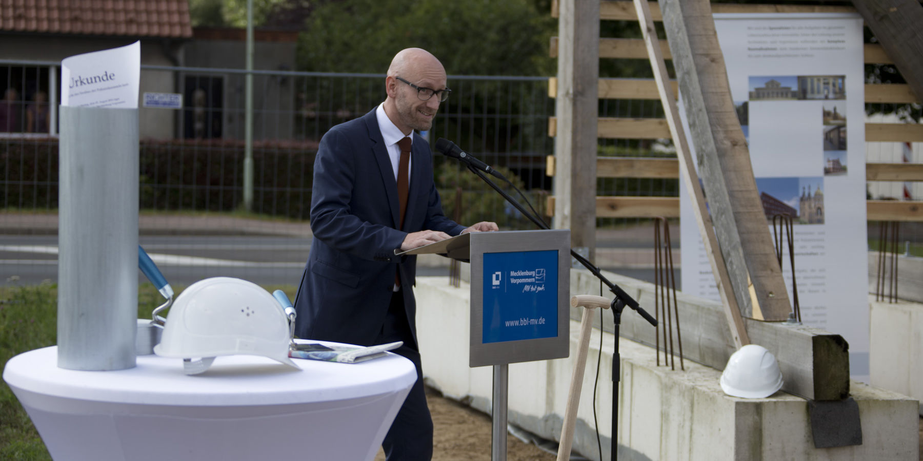 Robert Klaus vom landeseigenen Betrieb für Bau und Liegenschaften begrüßt als Vertreter des Bauherrn die Gäste und das Auditorium der Grundsteinlegung am 19. August 2019 auf dem Baufeld in Sanitz. © 2019 Betrieb für Bau und Liegenschaften Mecklenburg-Vorpommern