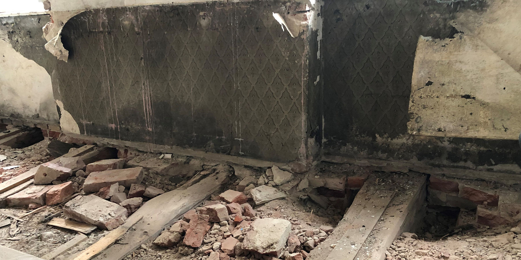 Im Obergeschoss des Kopfbaus des Nordflügels freigelegte Deckenbalken für die Balkenkopfsanierung - nach Abnahme der Holzverkleidung im Brüstungsbereich wurde hinter einer alten Zeitung aus dem Jahr 1868 eine historische Tapete entdeckt. © 2021 SBL Neubrandenburg