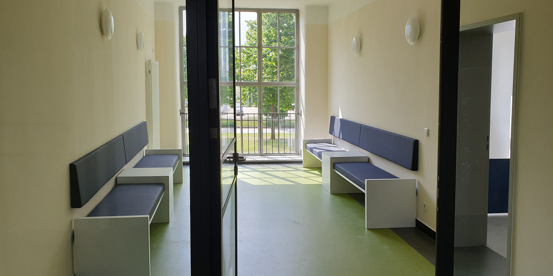 Die ehemaligen Treppenhauserweiterungen auf der Westseite mit den im Denkmalsinn wiederhergestellten bodengleichen Fenstern werden im Erdgeschoss des Gebäude 2 als Warteräume genutzt. © 2021 SBL Neubrandenburg