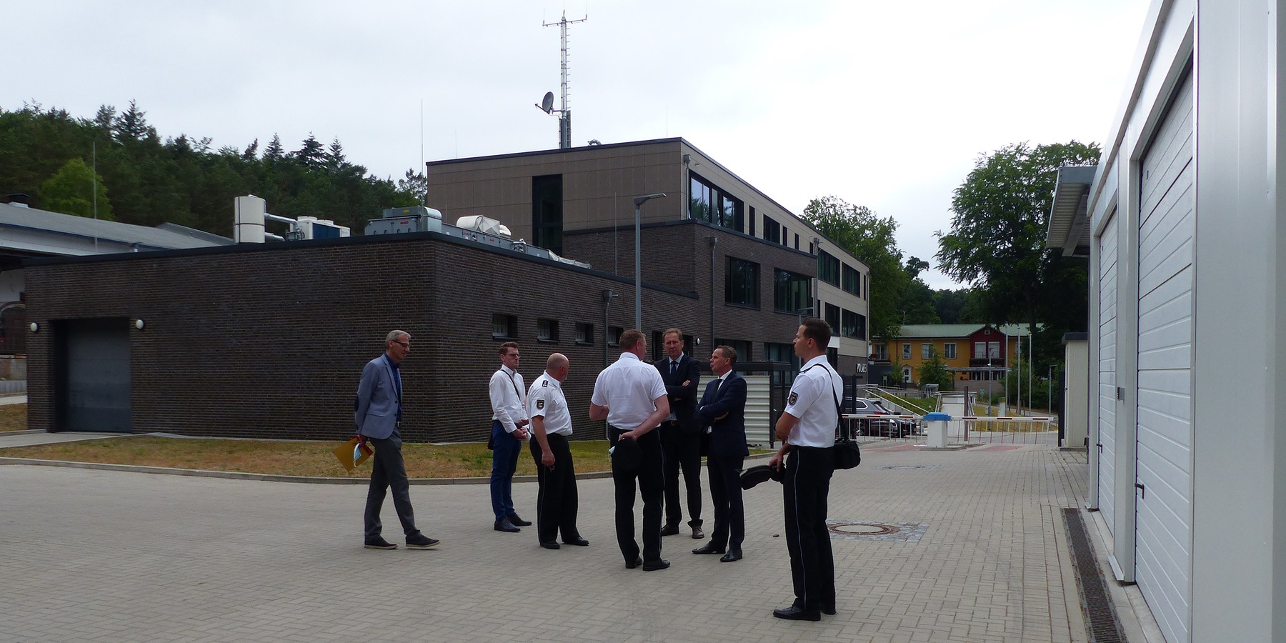 Besichtigung der rückwärtigen Außenanlagen mit Garagen, Carports und Stellplätzen - im Hintergrund der Polizeineubau mit eingeschossigem Gewahrsamstrakt © 2021 SBL Greifswald