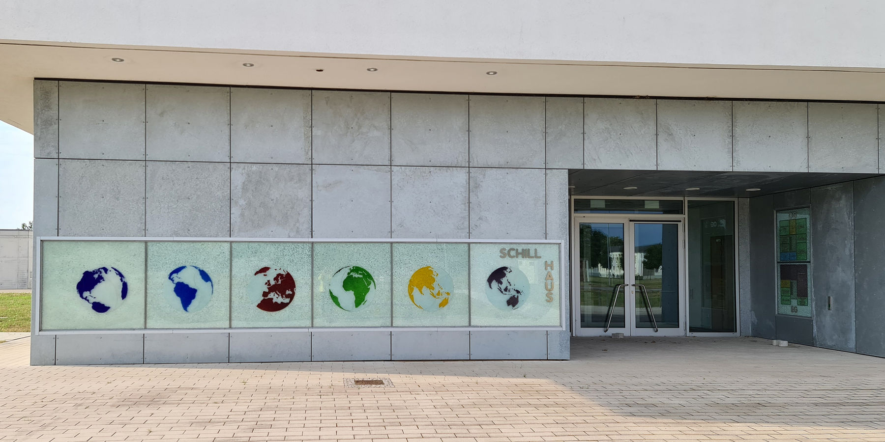 der Haupteingang mit dem im Rahmen der Kunst am Bau vom Künstler Olaf Thaler geschaffenen Hausschild und dem Gebäudewegweiser © 2021 SBL Neubrandenburg