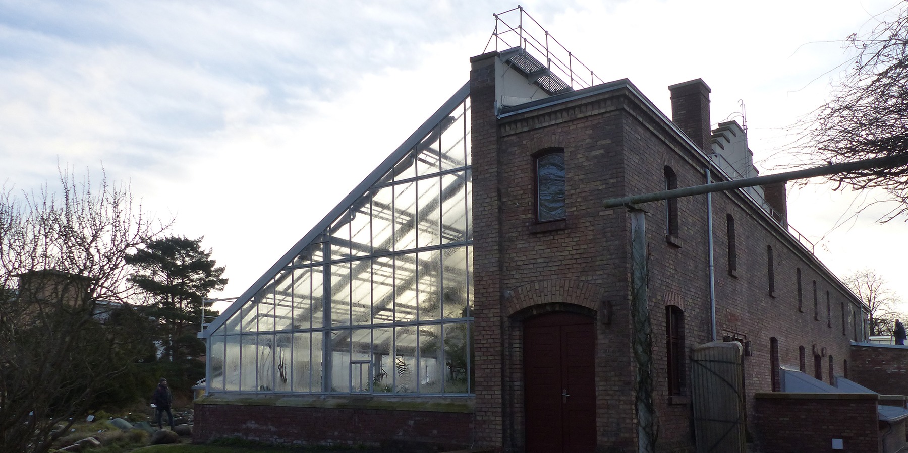 Blick von Westen auf die Gewächshausanlage mit rückwärtigem Sozialtrakt mit Fassade aus Backstein © 2021 SBL Greifswald