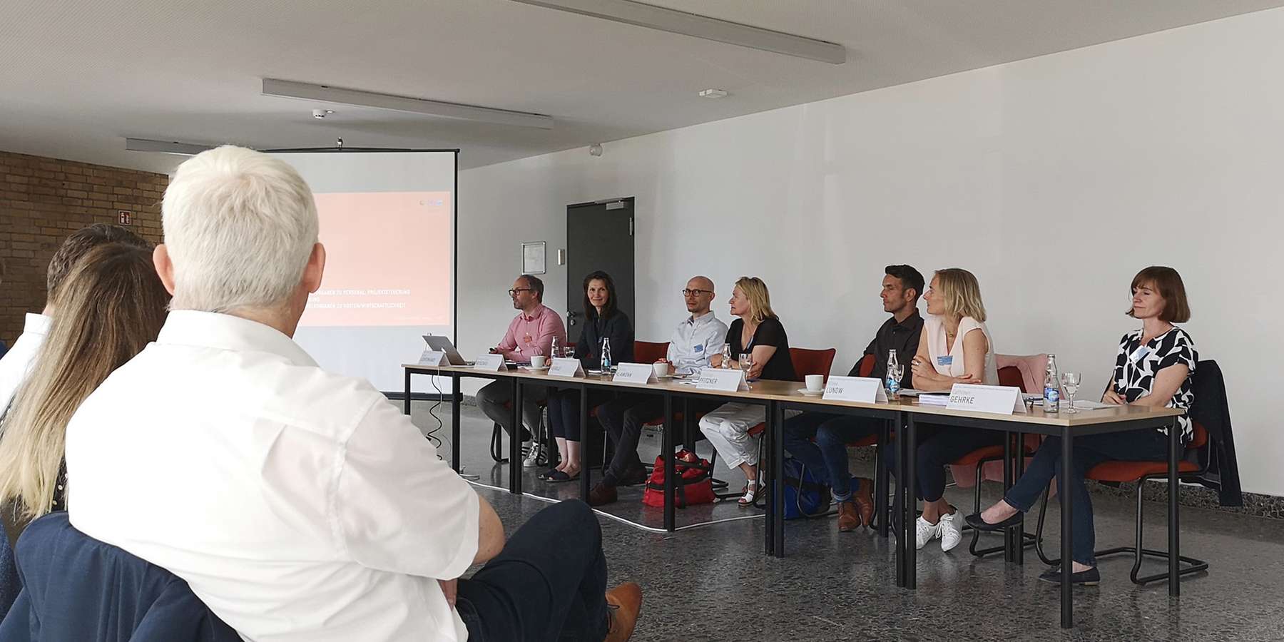 In einem Raum sitzen Menschen und schauen auf eine Leinwand. © 2022 Ilana Zorbas, SBL Rostock