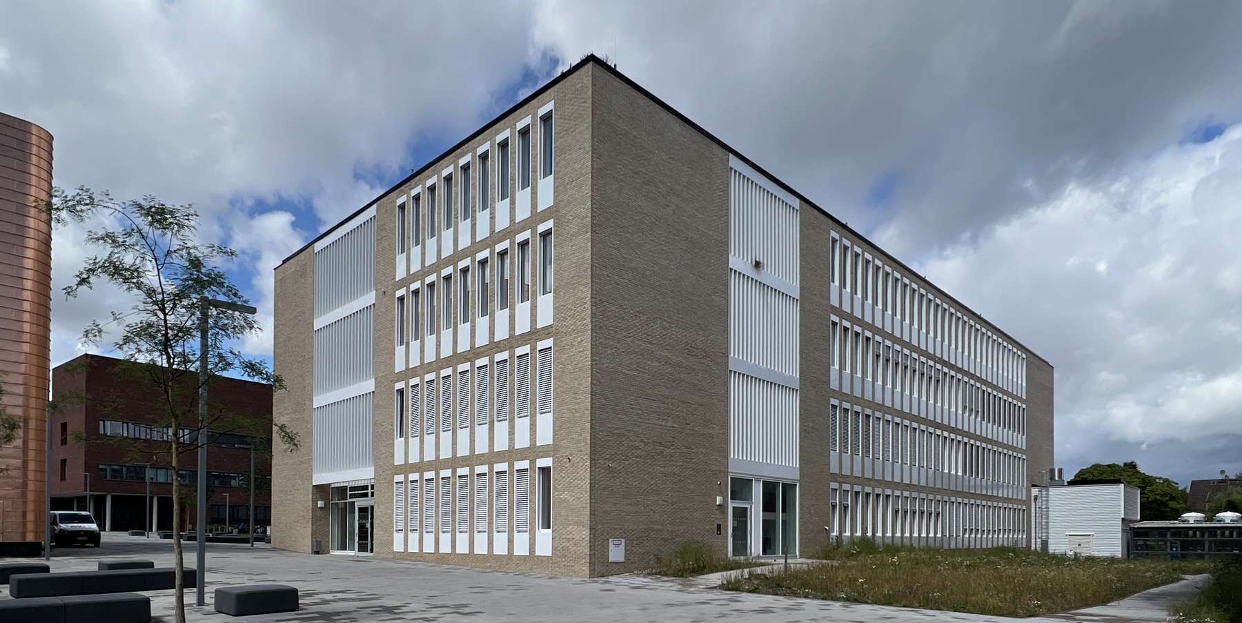 Gebäude in der Bildmitte, Himmel mit Wolken darüber, der Campus-Boulevard im Vordergrund © 2022 Christian Hoffmann (SBL-MV / Finanzministerium M-V)