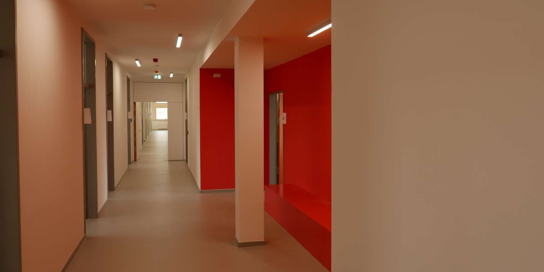 Die Kommunikationszonen in den Verkehrswegen wurden in den kräftigen Farben des jeweiligen Geschosses ausgeführt - hier ein langer Flur mit roten Nischen  © J.Rott