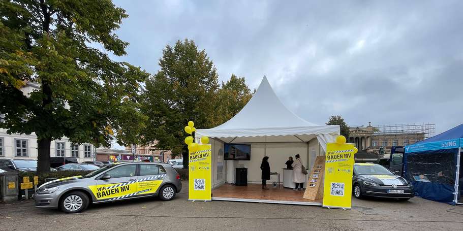 Dienst-PKW mit Claim  Wir bauen MV.  neben dem SBL-Stand in Schwerin. © 2022 Janine Chlebek (Finanzministerium MV / SBL-MV)