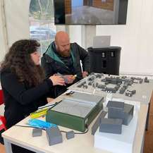 Majd Maayta und Mike Horn sitzen vor dem Modell des Campus der Hochschule Wismar. © 2022 Janine Chlebek (Finanzministerium MV / SBL-MV)