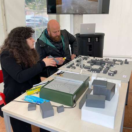 Majd Maayta und Mike Horn sitzen vor dem Modell des Campus der Hochschule Wismar. © 2022 Janine Chlebek (Finanzministerium MV / SBL-MV)