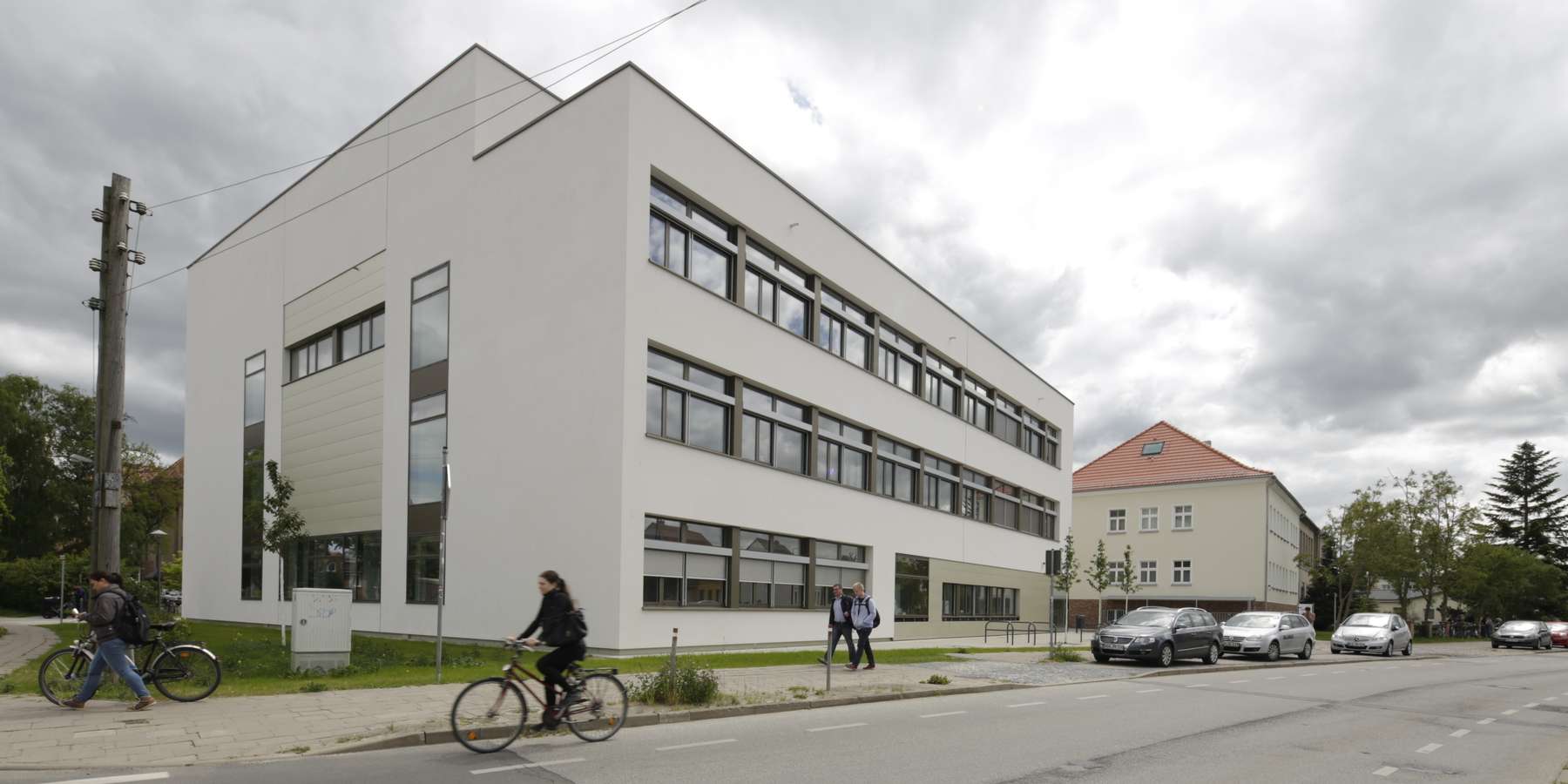 Fassade des Neubaus, Passanten und Radfahrer auf der Straße © 2015 Christian Hoffmann (BBL-MV / sbl-mv / Finanzministerium M-V)
