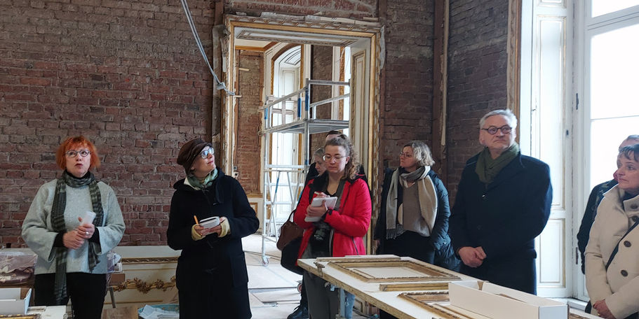 Erläuterungen zu Stuckdeckenfriesen und Weiß-Goldfassungen durch die Projektleitung Frau Dahl links © 2023 SBL Schwerin