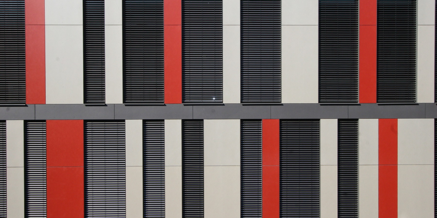 vertikale Fassadengliederung im Innenhof mit raumhohen Fenster-Elementen und ebenfalls raumhohen grauen und roten Fassadenplatten © 2007 Betrieb für Bau und Liegenschaften MV