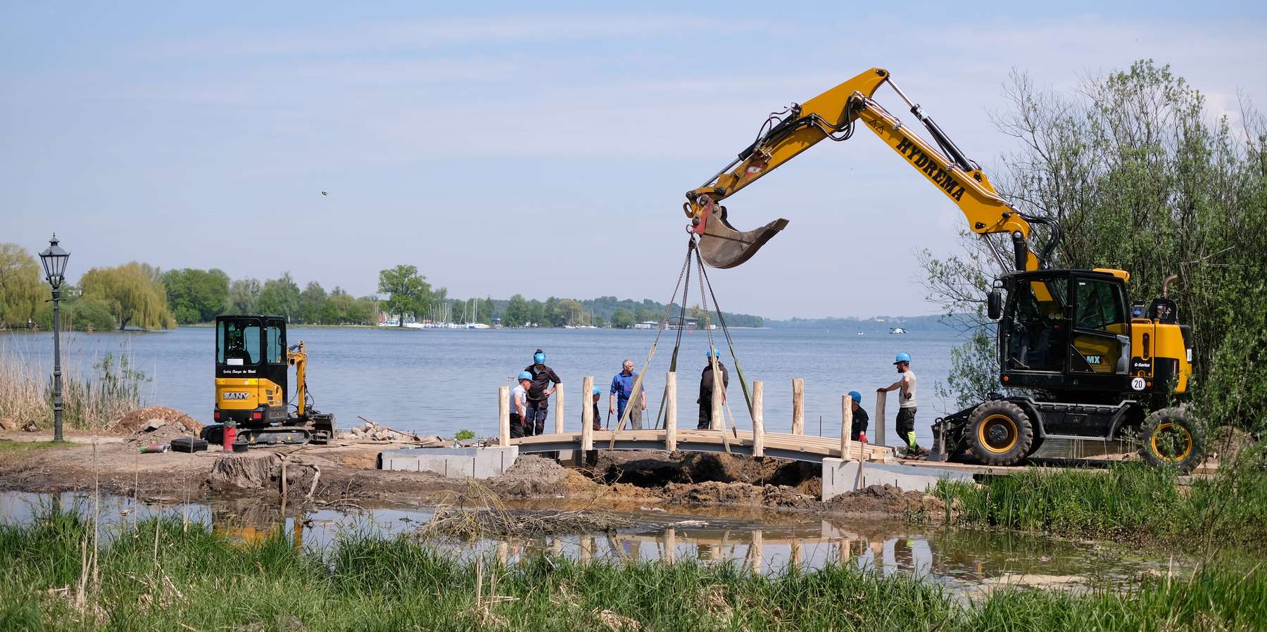 Ein Bagger hebt den Brückenüberbau auf die Widerlager. © 2023 SBL Schwerin