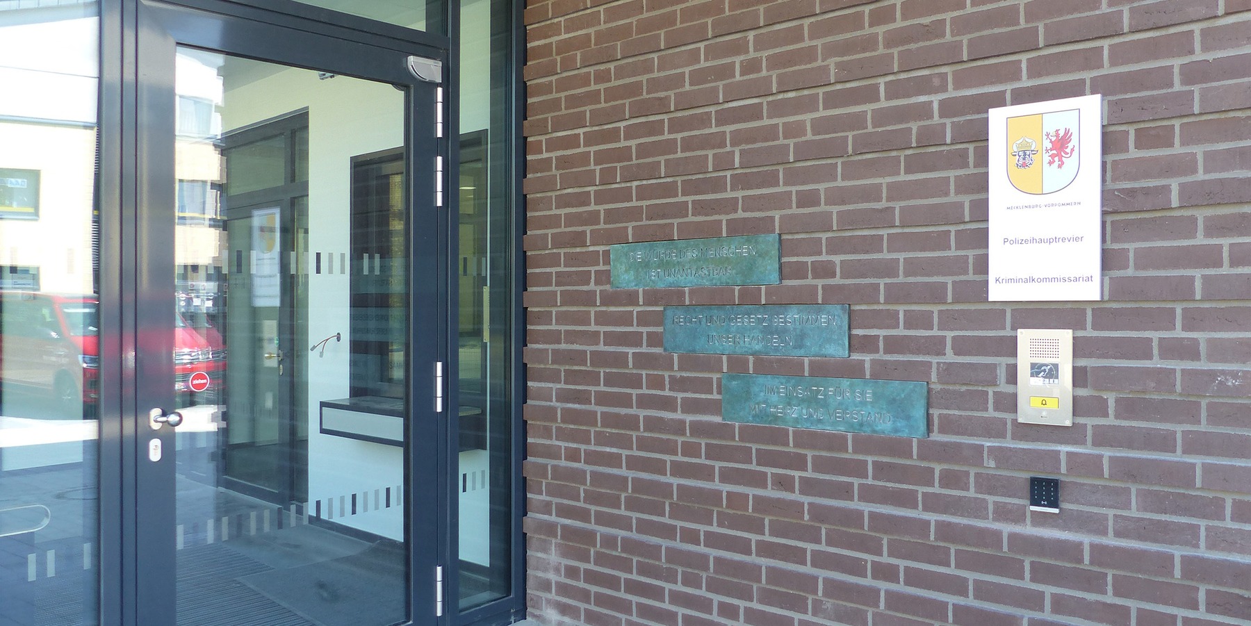 Überdachte Eingangszone mit Dienststellenbeschilderung und Schrifttafeln des Kunst am Bau-Objektes © 2023 SBL Greifswald