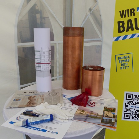 Die Kartusche und tagaktuelle Utensilien zu deren Befüllung liegen bereit: Baupläne, Urkunde, Tageszeitung, Münzen, Broschüre 20 Jahre Institut CM © 2023 SBL Greifswald