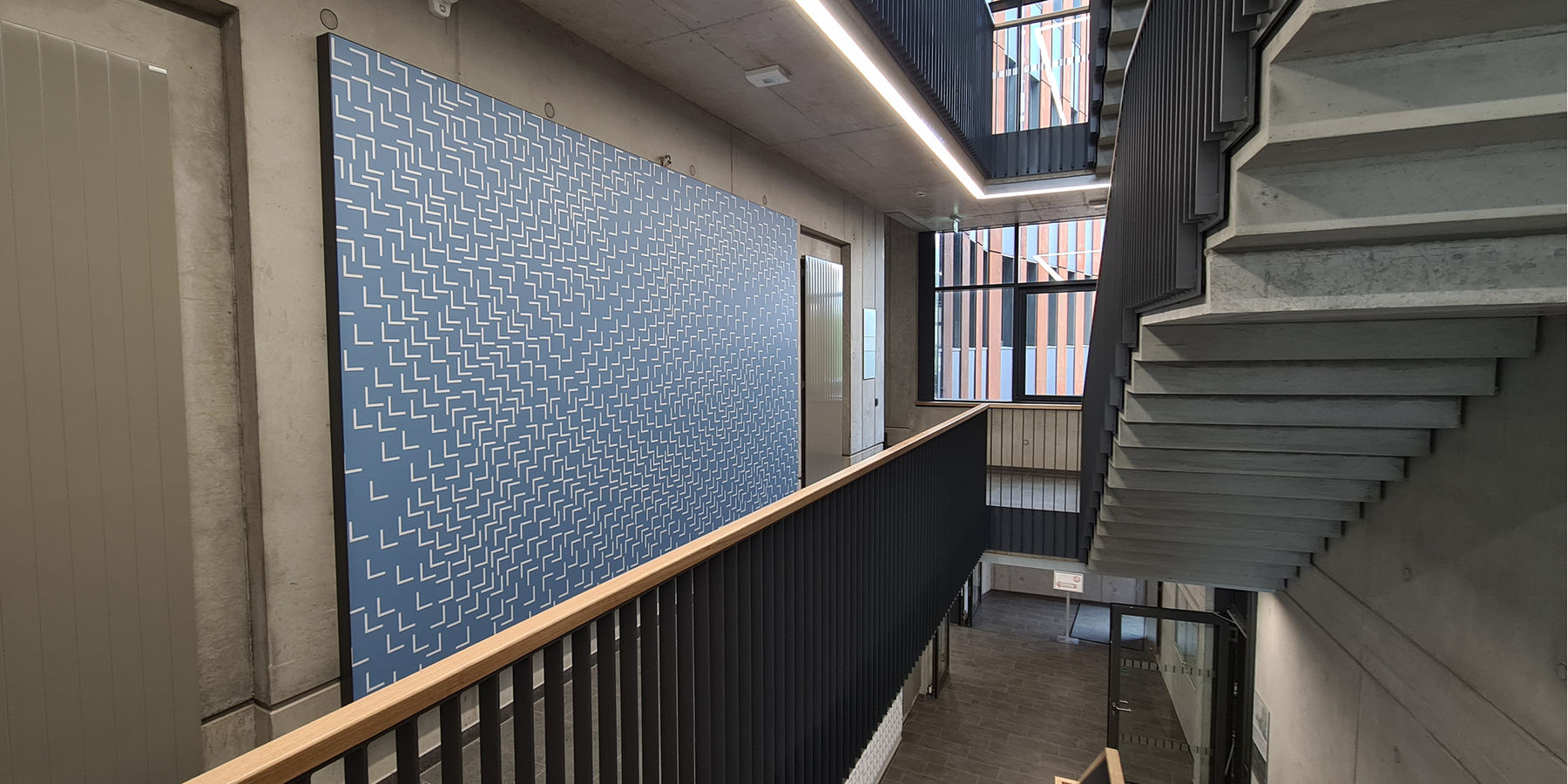 Blick in das Treppenhaus im 1. Obergeschoss mit der künstlerischen Gestaltung des Absorbers nach Entwürfen von Susanne Gabler © 2023 SBL Neubrandenburg