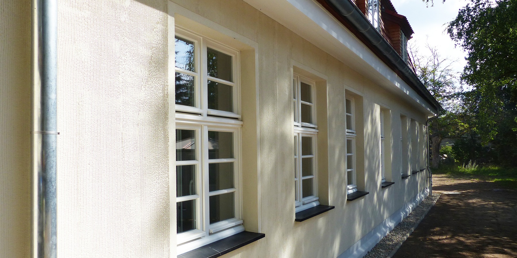 Rückseite des Gebäudes - der neue Außenputz, ein eingefärbter Strukturputz in Rillenoptik, wurde nach historischem Vorbild des nördlich gegenüberliegenden Altbaus originalgetreu wiederhergestellt © 2023 SBL Greifswald