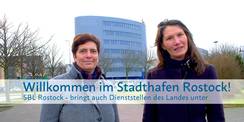Carmen-Alina Botezatu (re.) leitet das SBL Rostock und ist mit Sandra Auris (li.), Sachbearbeiterin Liegenschaftsmanagement im SBL Rostock, für die Unterbringung der aDiLaS verantwortlich. Im Hintergrund: Gebäude am Stadthafen in Rostock – dort ist u. a. © 2024 Christian Hoffmann (sbl-mv / Finanzministerium MV)