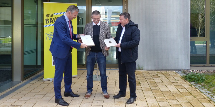 Finanzminister Dr. Heiko Geue und der stellvertretende Amtsleiter des SBL Greifswald Ralf Möwert übergeben gemeinsam die Silberplakette und das dazugehörige Zertifikat an den Direktor des URZ Prof. Ralf Schneider © 2024 SBL Greifswald