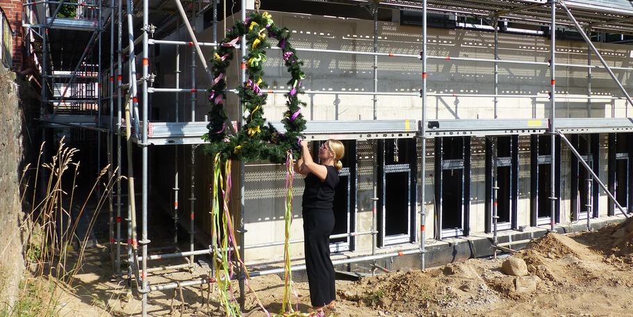 Der Rohbau ist geschmückt, Projektleiterin Aline Raether vom SBL Greifswald inspiziert noch ein letztes mal die Richtkrone © 2024 SBL Greifswald