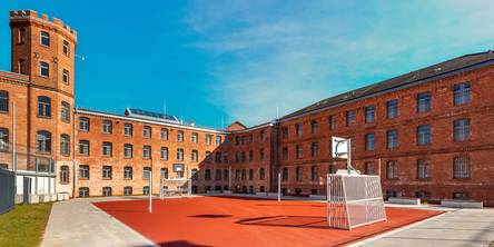 Das sanierte Hafthaus B mit dem Frauenvollzug und mit dem Transportzellenbereich im rechten Gebäudeteil, im Vordergrund der Freizeithof mit Kleinspielfeld. © 2025 Christoph Meyer/Paperheroes