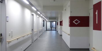 Blick in den Flur einer Patientenpflegestation im Obergeschoss mit Kennzeichnung der Zugänge zu den Patientenzimmern © 2019 Betrieb für Bau und Liegenschaften Mecklenburg-Vorpommern