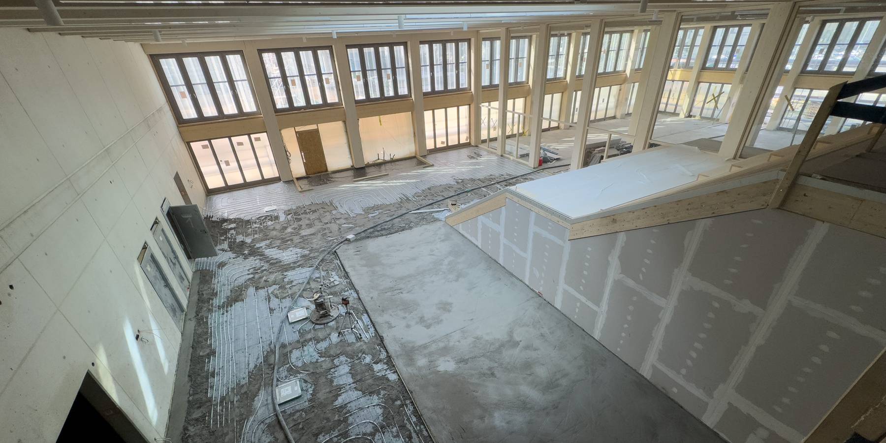 Innenausbau läuft! Hier wird der Estrich der Mensa gegossen (links). In der Cafeteria (rechts) ist der Fußboden bereits fertig. © 2025 SBL-MV (Ministerium für Finanzen und Digitalisierung Mecklenburg-Vorpommern)