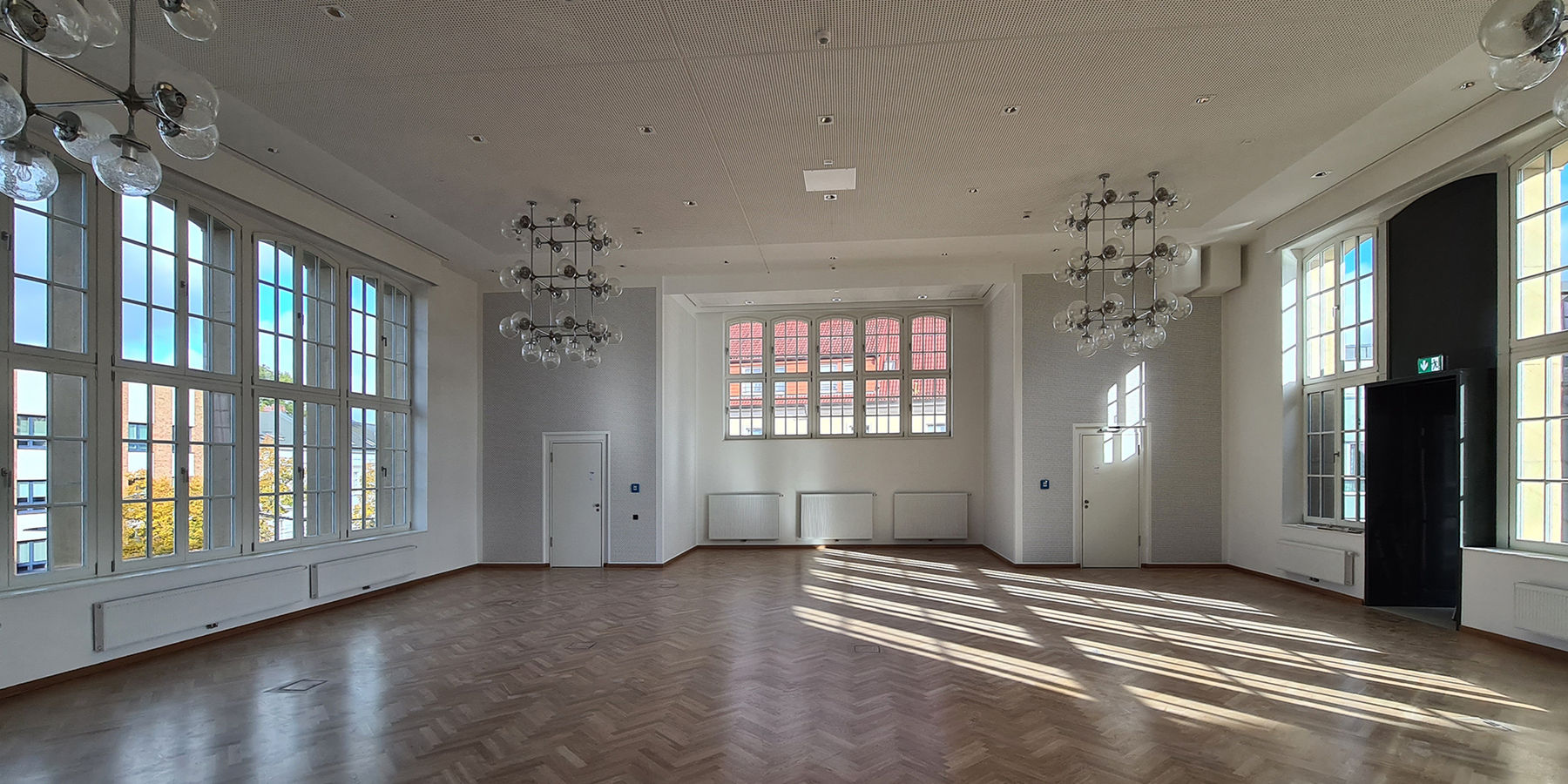 Blick in den großen Beratungsraum des StALU mit den vorhandenen Lampen aus der DDR-Zeit. Rechts schließt der Verbindungsgang zum Haus 5 an. © 2025 SBL Neubrandenburg