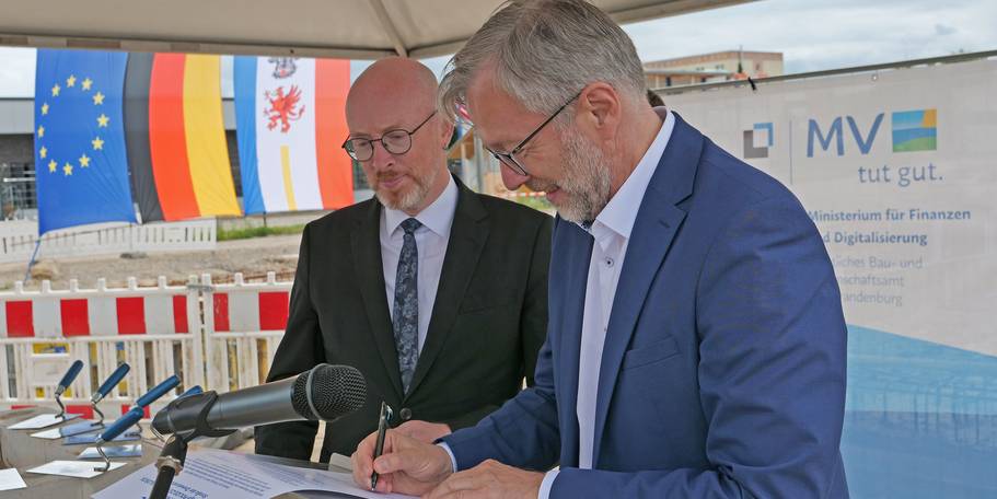 Innenminister Christian Pegel (li.) und Finanzminister Dr. Heiko Geue unterschreiben die Urkunde der  Grundsteinlegung. © 2026 SBL Neubrandenburg