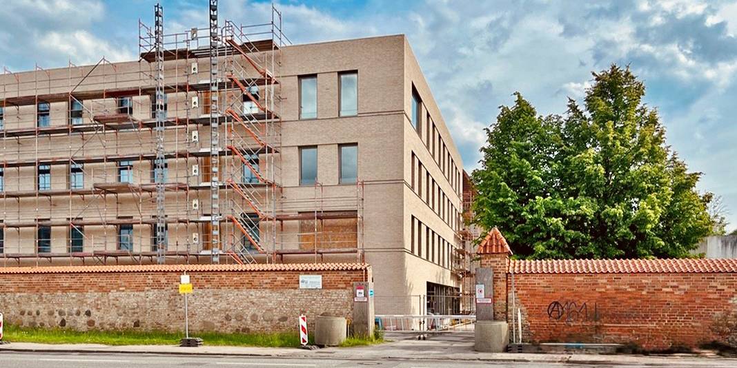 Blick auf die Baustelle im Juni 2026 - das Gerüst ist fast vollständig gefallen, die Fassade wird deutlich sichtbar. © 2026 SBL Rostock