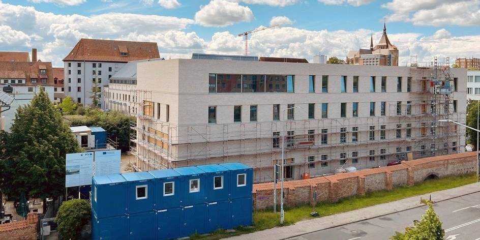 Blick auf die Baustelle im Juni 2026 - das Gerüst ist fast vollständig gefallen, die Fassade wird deutlich sichtbar. © 2026 SBL Rostock