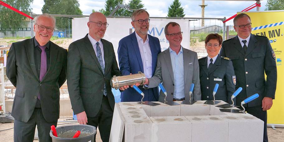 Befüllte  Zeitkapsel  präsentieren (von links) Baudirektor Jens Rott, Minister für Inneres und Bau Christian Pegel, Minister für Finanzen und Digitalisierung Dr. Heiko Geue, Landtagsabgeordneter Dirk Stamer, Polizeipräsidentin von Rostock Anja Hamann und  © 2026 SBL Neubrandenburg