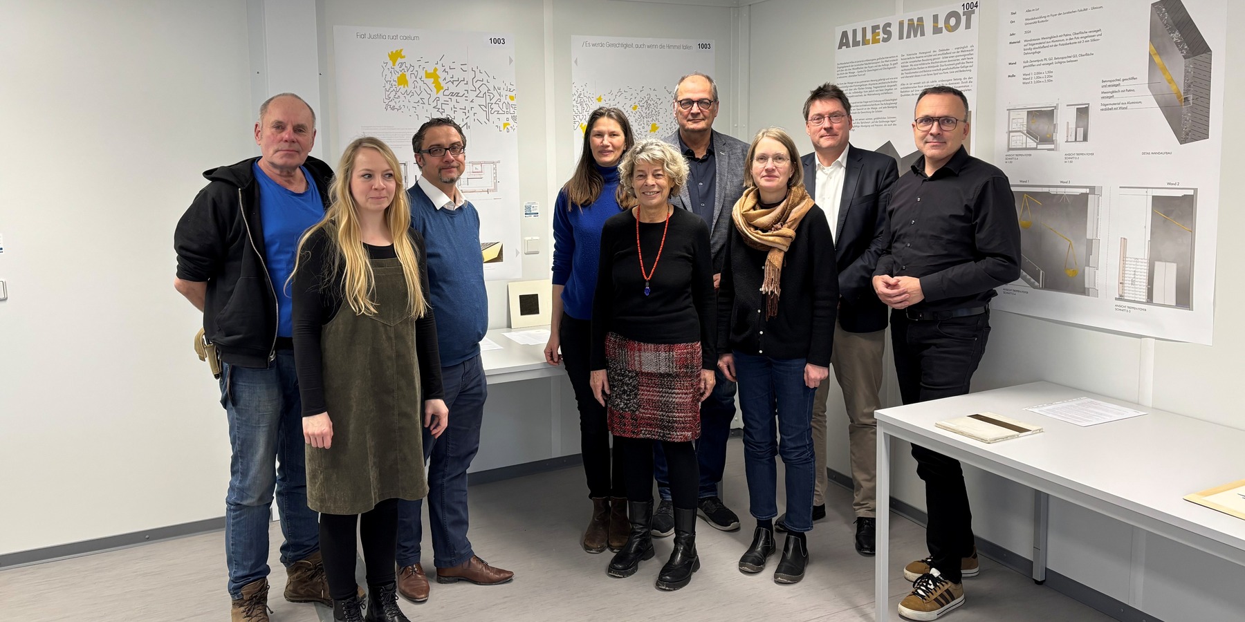 Das Preisgericht vor dem Siegerentwurf (von links: Holger Stark, Catleen Hofbauer, Thomas Möller, Carmen-Alina Botezatu, Petra Steeger, Bernd Kommnick, Claudia Lochmann, Prof. Dr. Carsten Kremer und Christoph Meyn). © 2026 SBL Rostock